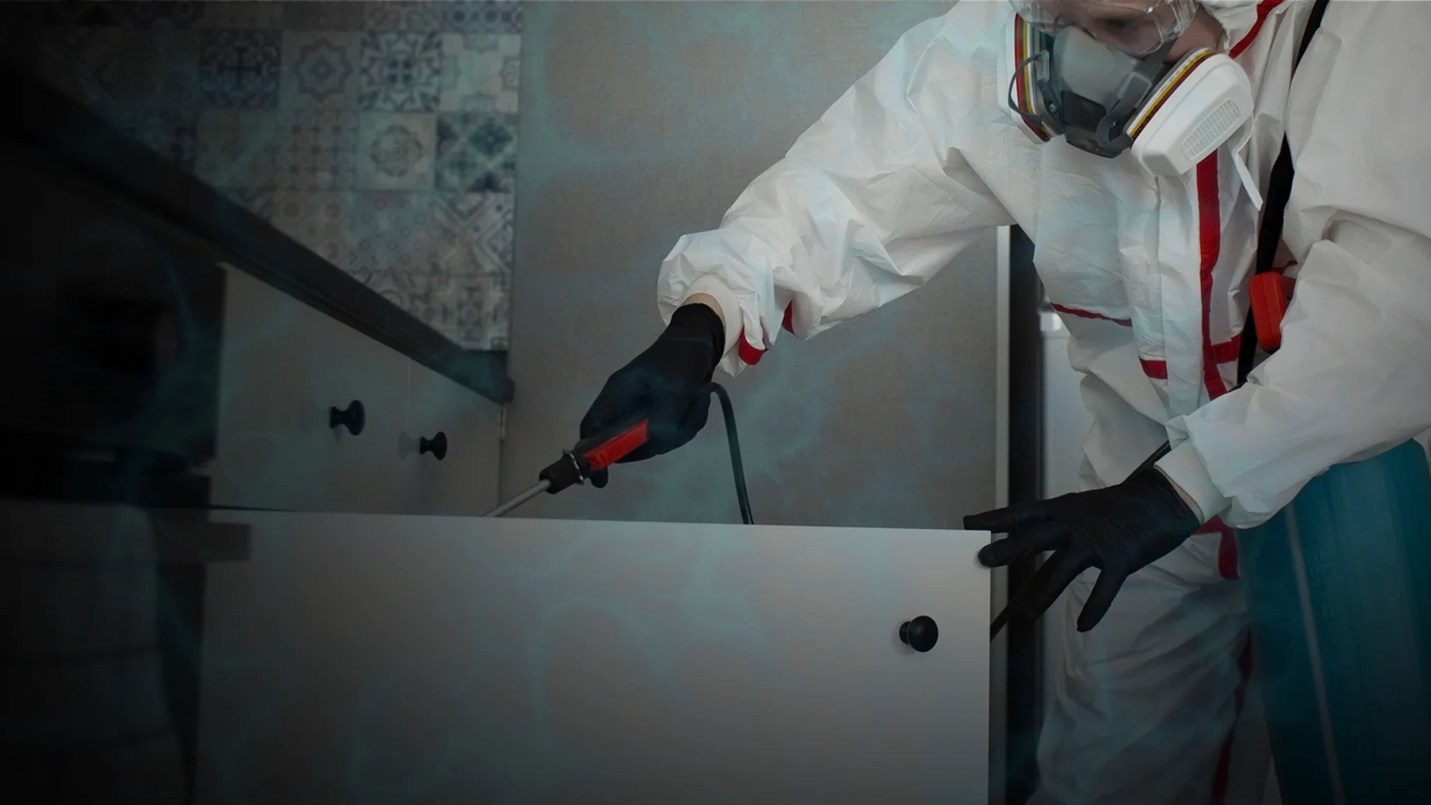 a man in safety suit with gas mask and pest treatment equipment wearing black nitrile gloves
